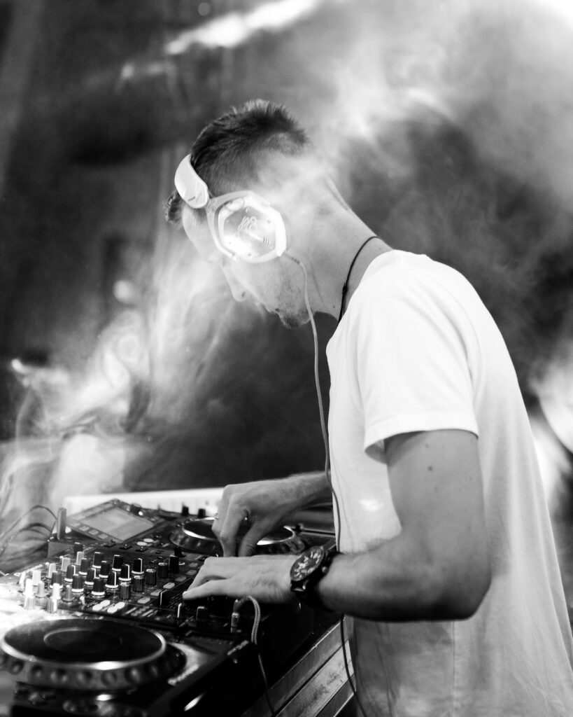 pexels-photo-1694908-1694908 Black and white photo of a DJ mixing music with dynamic smoke effects and lighting.